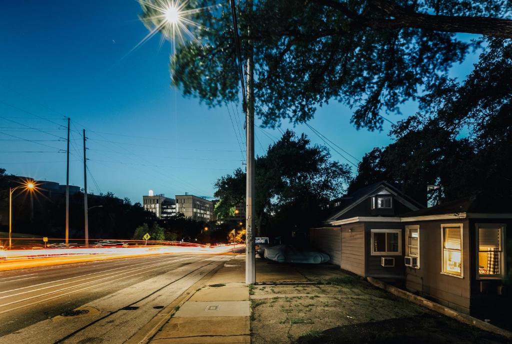a street with a tree and a house and street lights at Two Tree-House Oasis on UT Campus in Austin