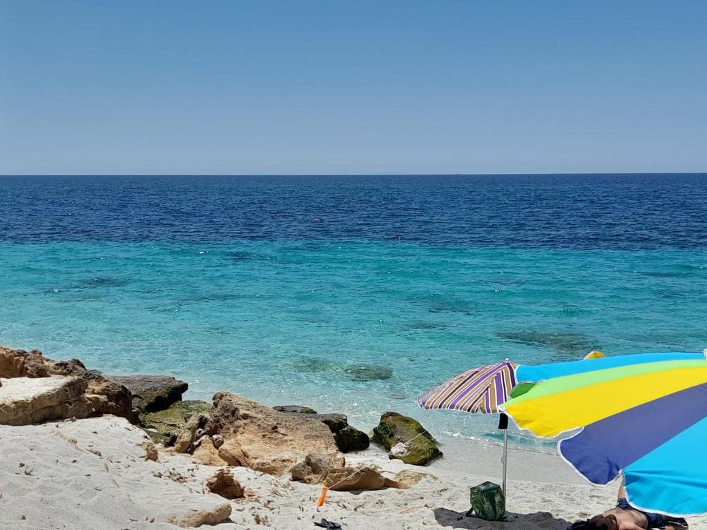 a colorful umbrella on a beach with the ocean at Sardegna Calaverde Villetta in Forte Village