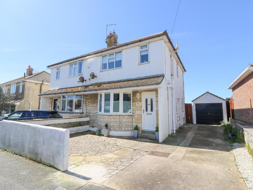 une maison blanche avec une voiture garée devant elle dans l'établissement Lagoon View, à Weymouth
