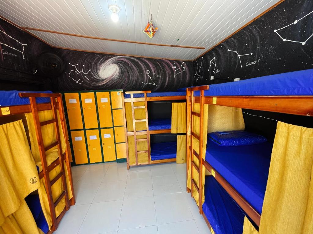 a room with three bunk beds and a wall with drawings on it at Hostel Caiçara Maresias in São Sebastião