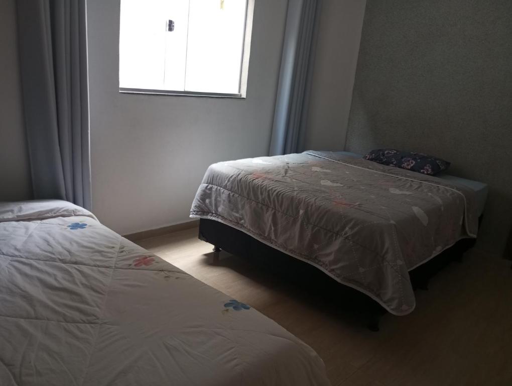 a bedroom with two beds and a window at Apartamento Flat in Anápolis