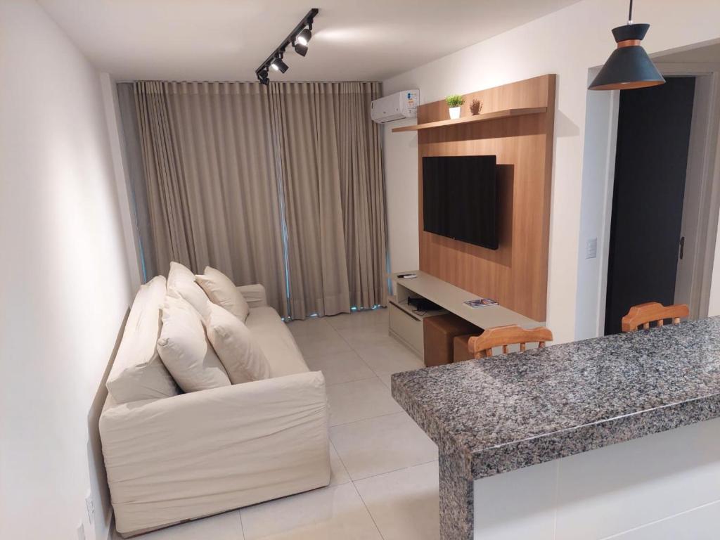 uma sala de estar com um sofá branco e uma televisão em Apartamento Novo em Ondina em Salvador