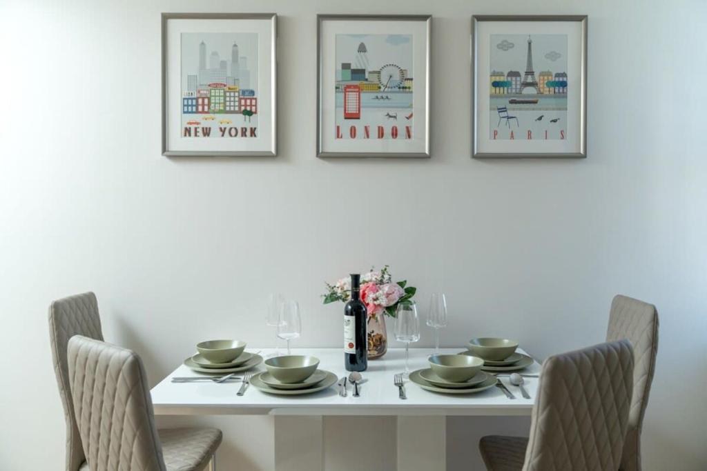 a white dining room table with three pictures on the wall at City of London Lovely Two Bedroom Apartment in London