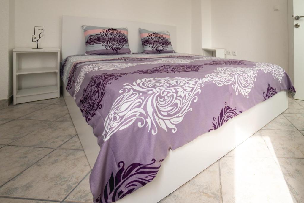 uma cama roxa e branca num quarto branco em Fox Apartment em Gevgelija