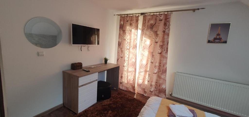 Schlafzimmer mit einem Schreibtisch und einem TV an der Wand in der Unterkunft Casa Yna in Horezu
