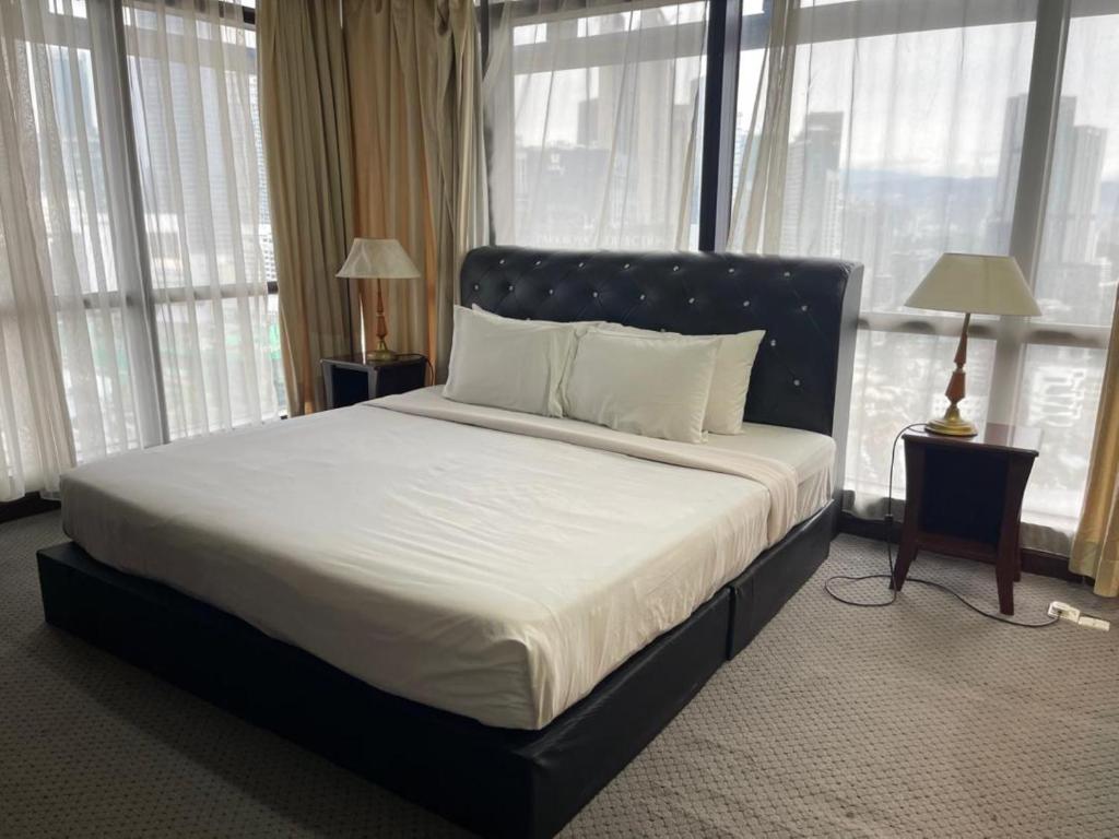 a bedroom with a large bed with white sheets and windows at The Hotel and Apartment At Berjaya Times Square in Kuala Lumpur