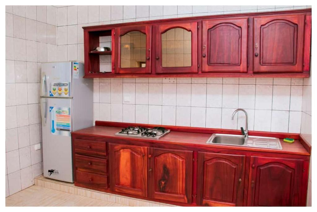 a kitchen with red cabinets and a white refrigerator at Résidences K and D in Bafoussam
