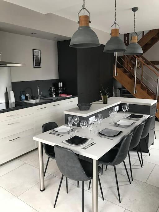 - une cuisine avec une table, des chaises et des verres à vin dans l'établissement L’Écho des Vagues, Cherbourg en Cotentin, à Cherbourg en Cotentin