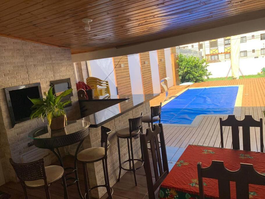 a kitchen with a bar with chairs and a swimming pool at Casa com Piscina em Região Nobre de Cascavel in Cascavel