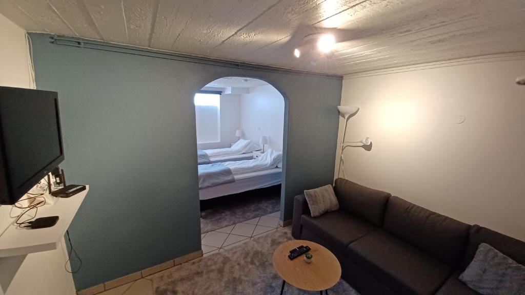 a living room with a couch and a room with a bed at Basement hideaway in Akureyri