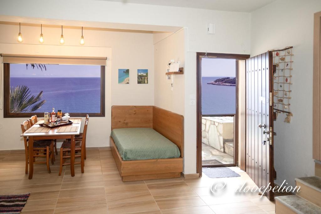 a room with a bed and a table with a view of the ocean at Uranus Blue Residence Agios Ioannis Papa Nero in Agios Ioannis Pelio