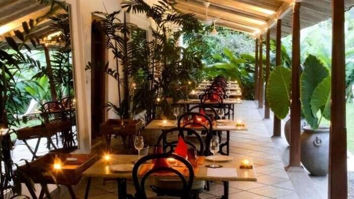 a row of tables in a restaurant with plants at UdayaCK in Naranpanawa