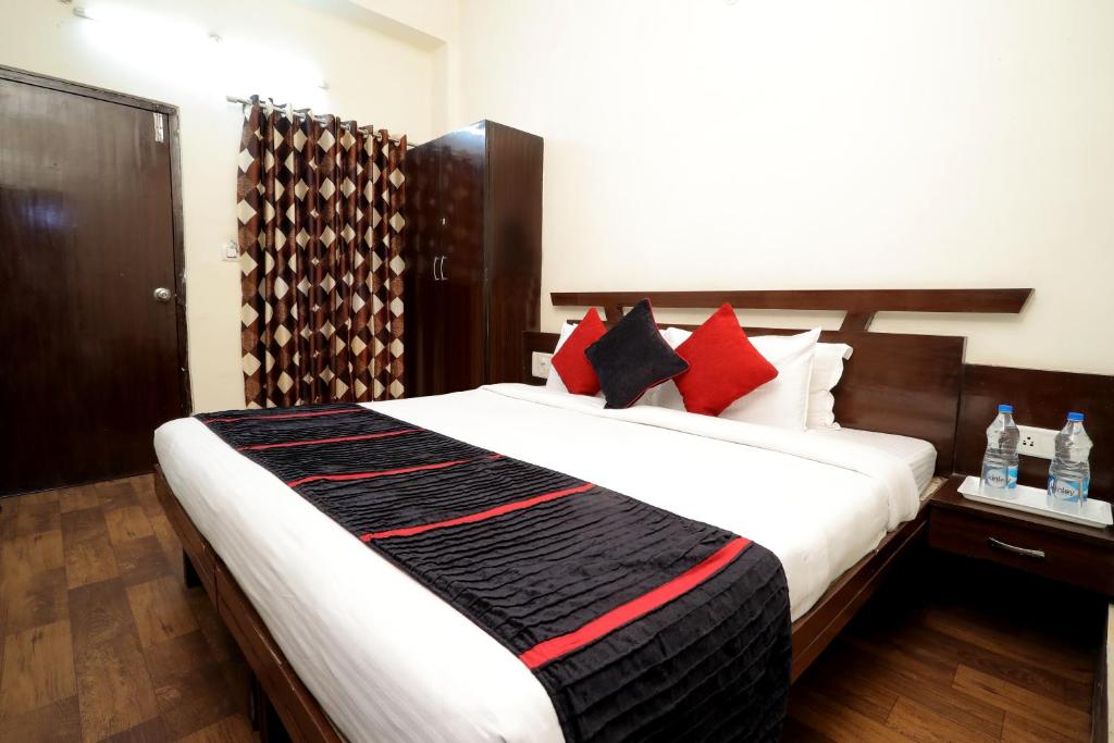 a bedroom with a large bed with red and black pillows at TRP VIVEK CONTINENTAL in Gwalior