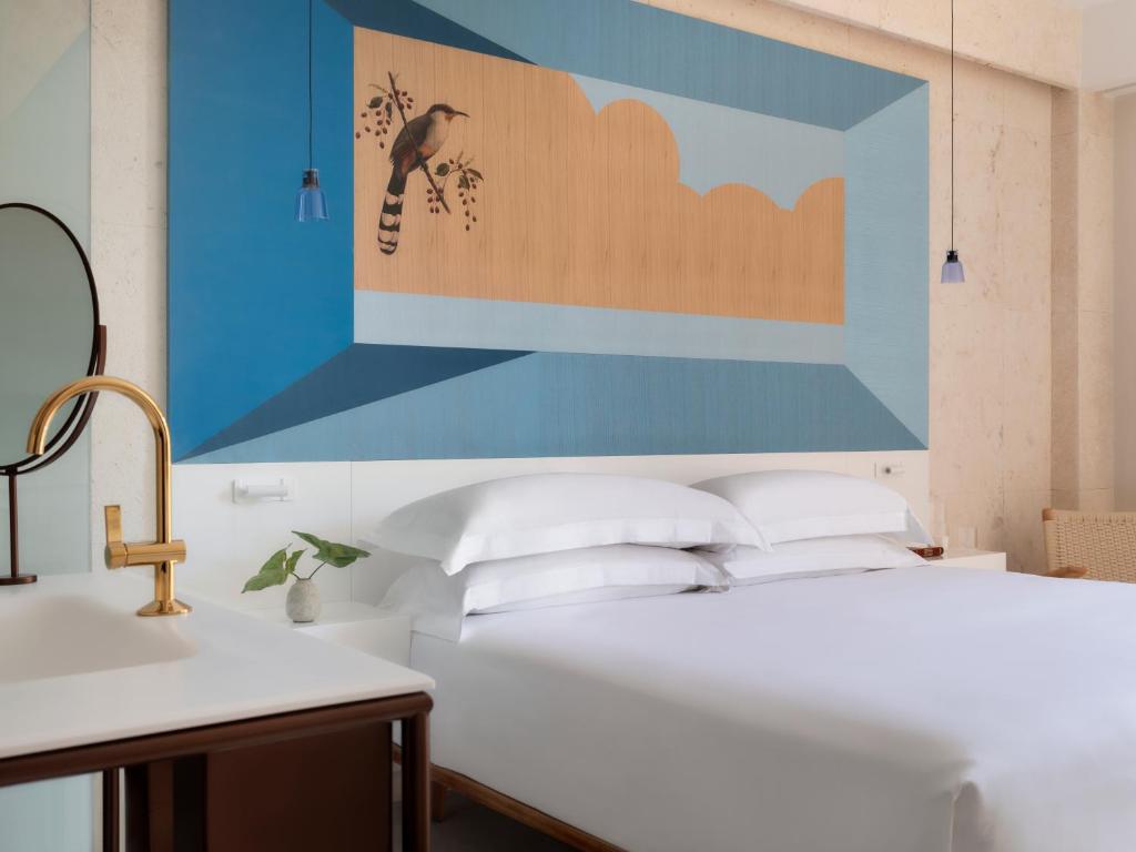 ein Schlafzimmer mit einem Bett mit einem großen Gemälde an der Wand in der Unterkunft Kimpton Las Mercedes, an IHG Hotel in Santo Domingo