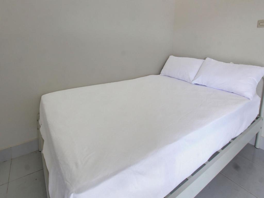 ein kleines weißes Bett mit weißer Bettwäsche und Kissen in der Unterkunft OYO Life 92769 Janigo Kos in Tanjungkarang