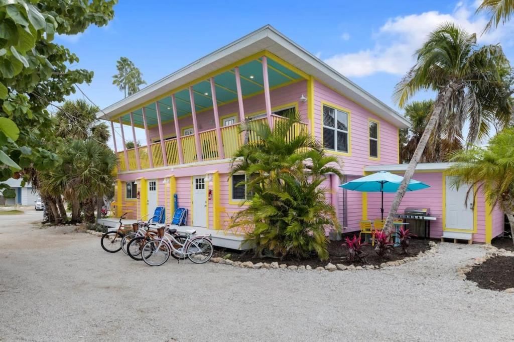ein rosa und gelbes Haus mit Fahrrädern, die vorne geparkt sind in der Unterkunft Charming Suite with Balcony and Bikes at Historic Sandpiper Inn in Sanibel