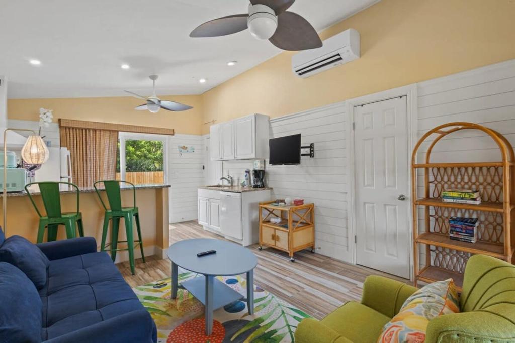 a living room with a blue couch and a kitchen at Renovated Cottage at the Historic Palms Inn of Sanibel- Includes Pool and Bikes in Sanibel