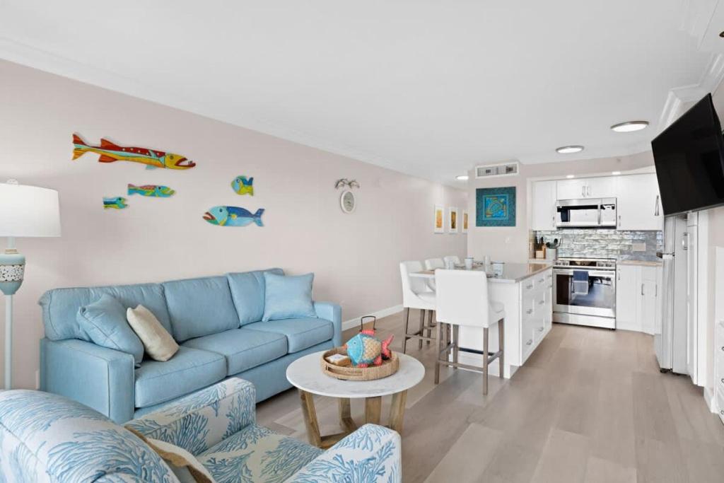 a living room with a blue couch and a kitchen at Family-Friendly Bayside Villa at South Seas Resort in Captiva