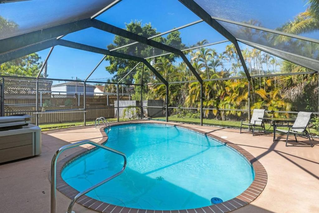 a large swimming pool with a patio with a table and chairs at Cute Coastal Home with Pool in Fort Myers