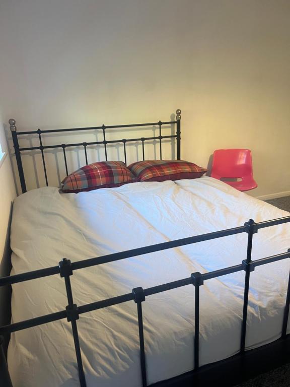 a bed with two pillows and a red chair at double room in New Barnet