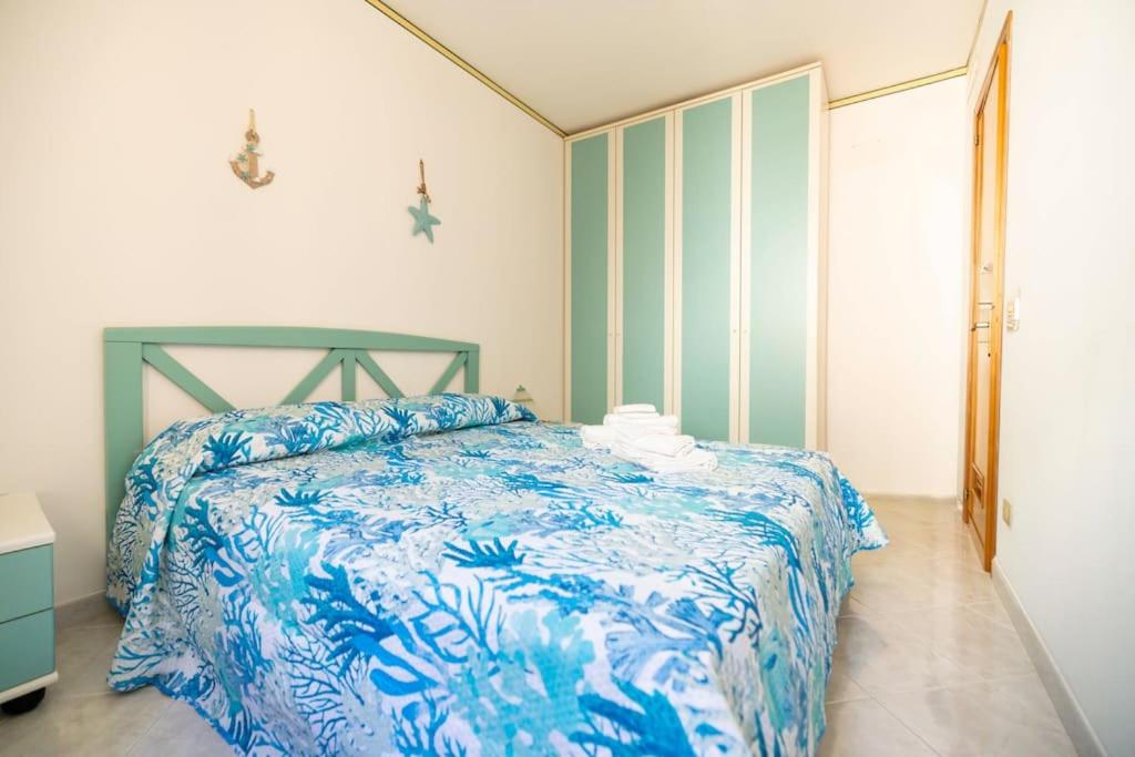 ein Schlafzimmer mit einem Bett mit einer blau-weißen Bettdecke in der Unterkunft Calasole House: Mare a 2 Passi in San Vito lo Capo