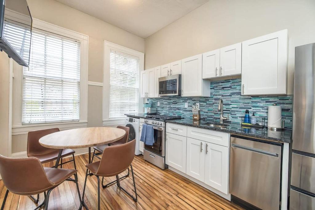 a kitchen with white cabinets and a table and chairs at Charming Condo in Historic Downtown Building in Wilmington
