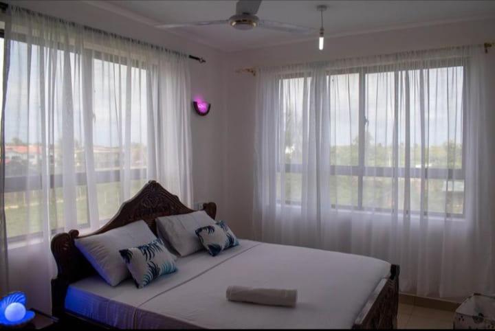 um quarto com uma cama com almofadas e janelas em Modern 1bedroom 5 min walk to the beach near Severine Neptune beach resort behind go kart em Mombasa