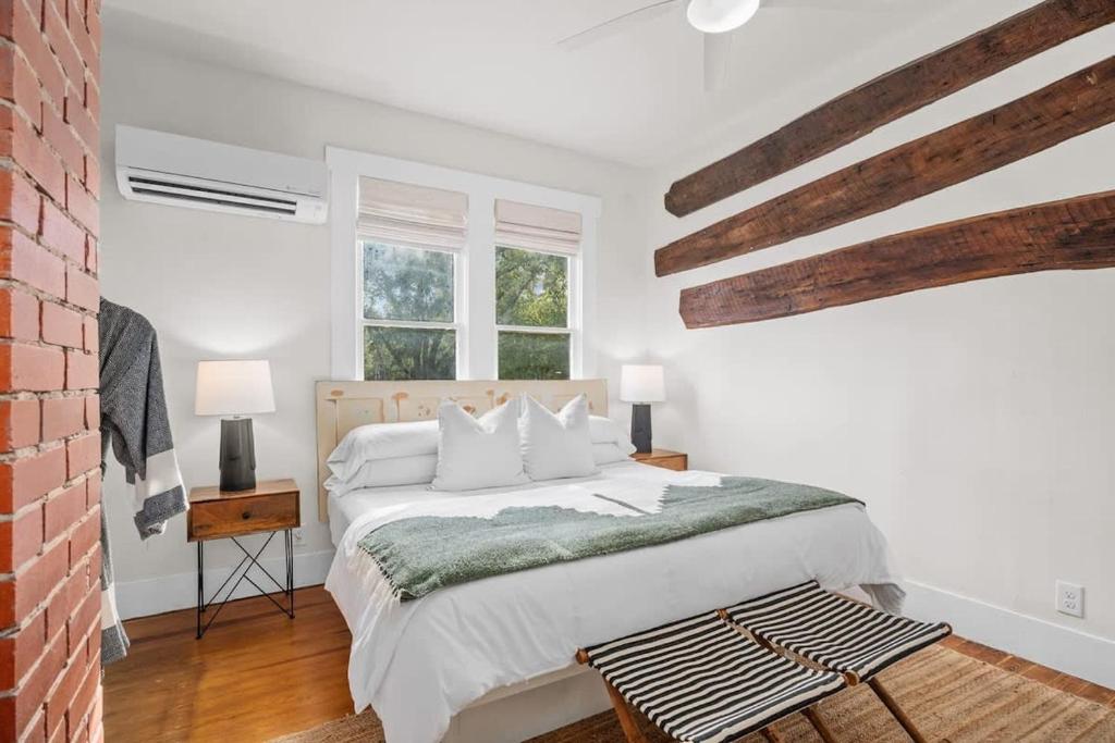 a white bedroom with a bed and a brick wall at The Downtown Studio 1 private hot tub in Fredericksburg