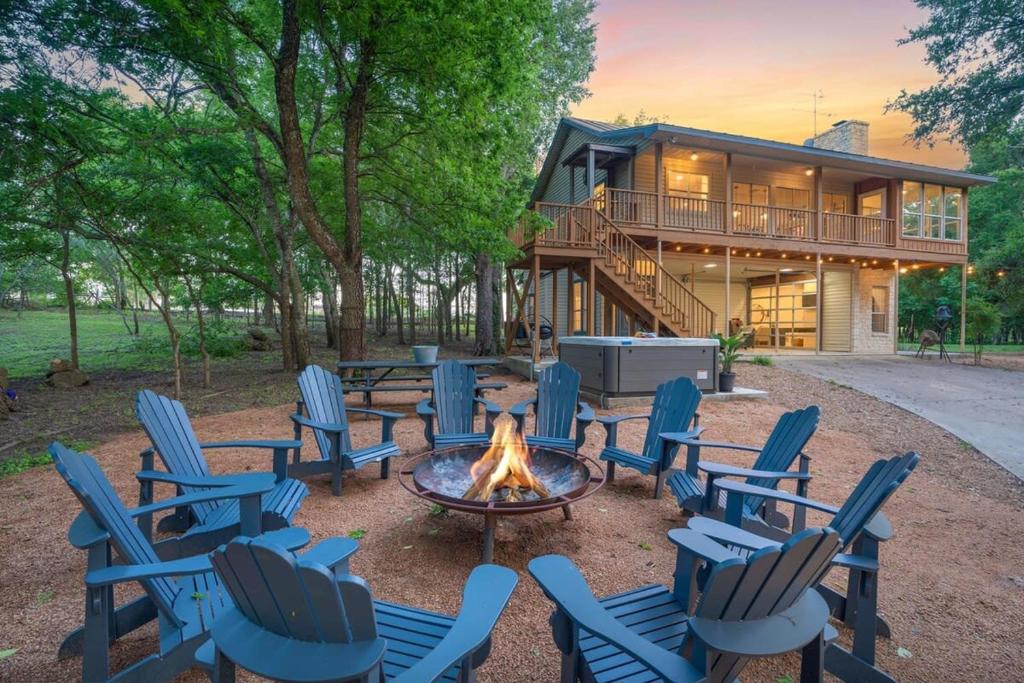 a group of chairs around a fire pit in front of a house at Rio Ranchito, Hot tub, River front, Fire Pit! in Stonewall
