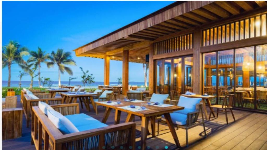 een restaurant met tafels en stoelen op een terras bij Alma Resort in Thôn Mỹ Ca
