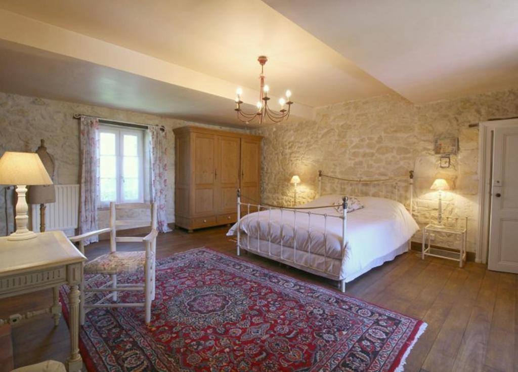 a bedroom with a bed and a table and a rug at Chambre d'hôtes spacieuse, salle de bain privative in Saint-Michel-de-Fronsac