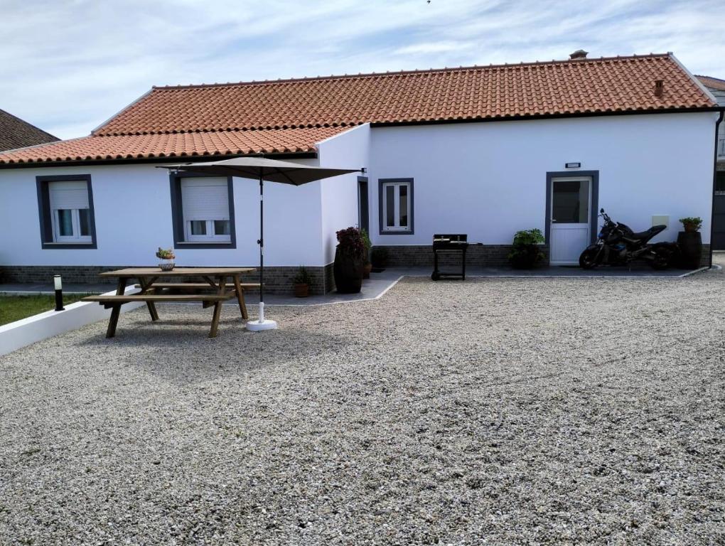 une maison blanche avec une table de pique-nique et un parasol dans l'établissement Casa da Pitoquinha II, à Óbidos