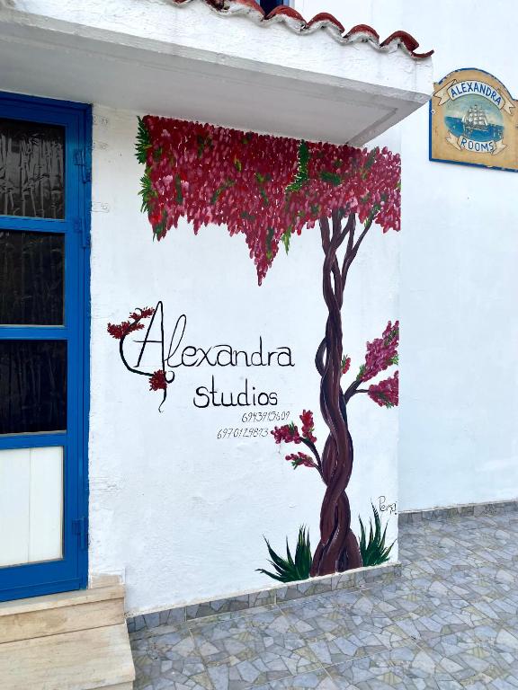 un cartello su un edificio con un albero fiorito di Alexandra Studios a Néos Pírgos