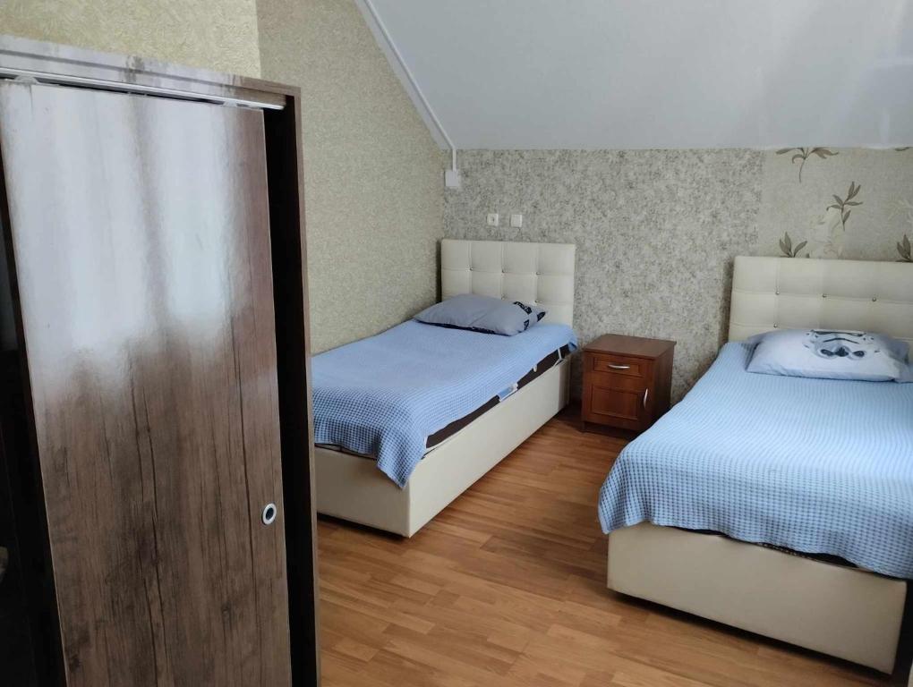 a bedroom with two beds and a wooden floor at Natali & Giga in Ureki