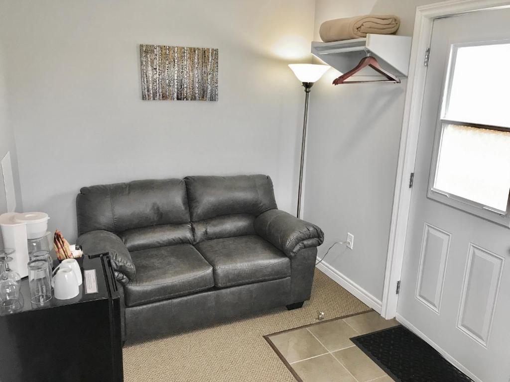 a black leather couch in a room with a door at Stay in Gros Morne in Rocky Harbour