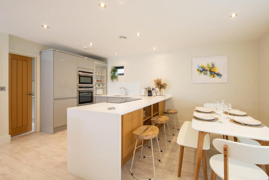 a kitchen with a white island and a table and chairs at Designer Family Escape Hot Tub Steps to Beach in East Wittering