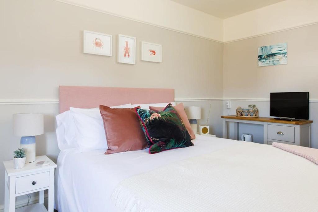 1 dormitorio con cama blanca con almohadas y TV en Camber - King Room in Gastro Pub, en West Wittering