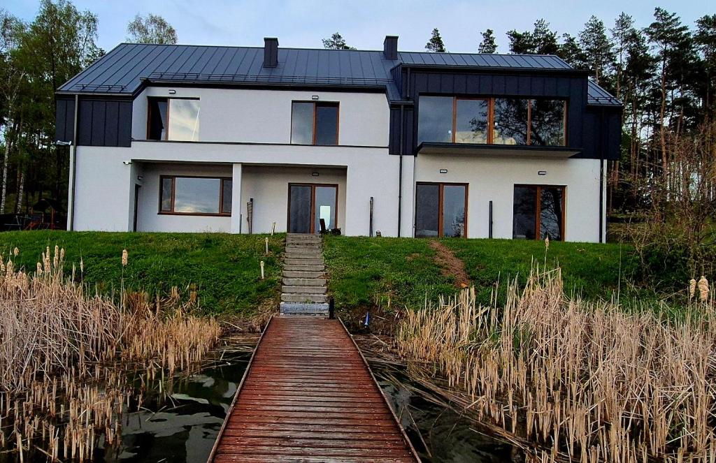 a house on a hill with a wooden path leading to it at LAKE VIEW Apartamenty in Brodnica