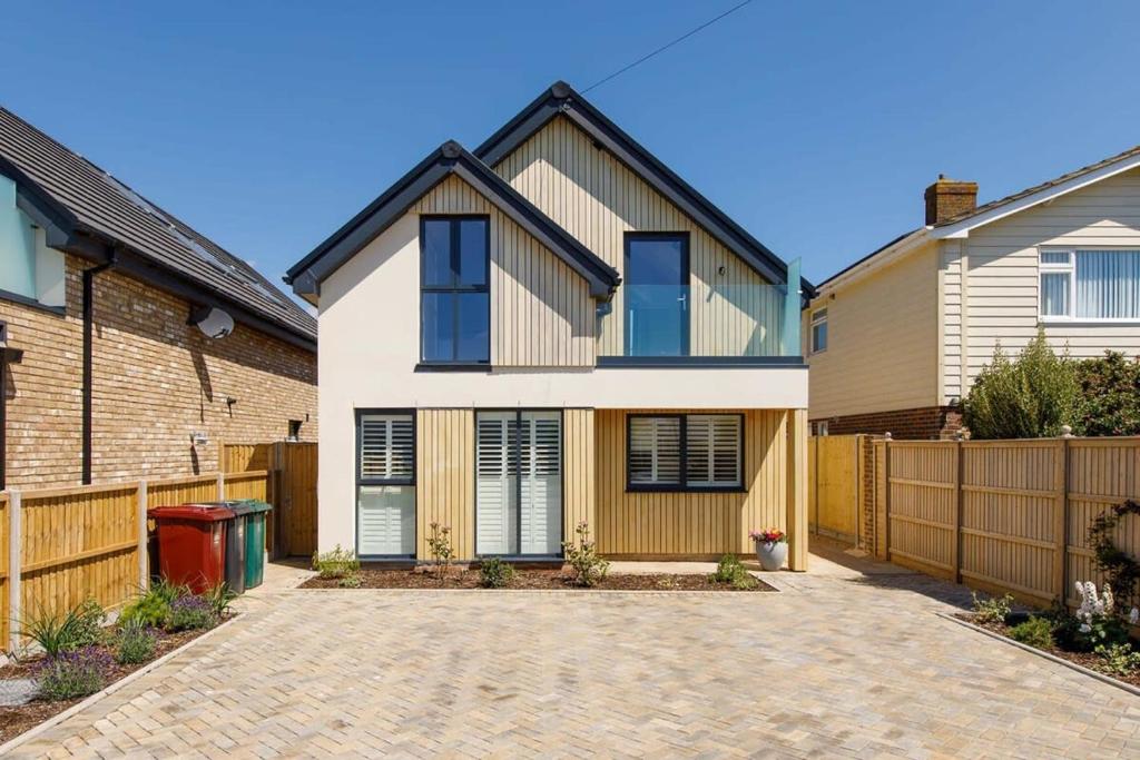 a house with a fence in front of it at Luxury designer coastal home for 10 with hot tub in West Wittering