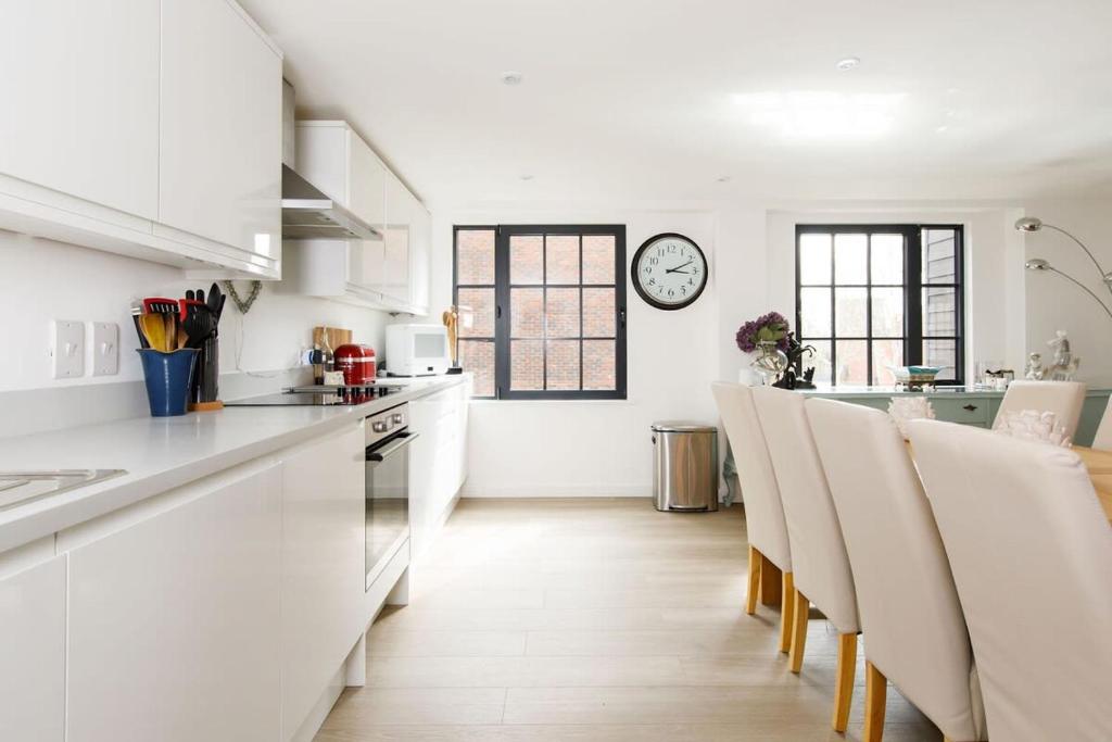 a kitchen with white counters and a clock on the wall at Stylish City Centre Apartment with Sauna in Chichester