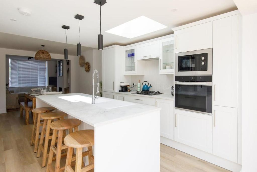a kitchen with white cabinets and a large island with bar stools at Stylish 2 Bed City Stay in Chichester