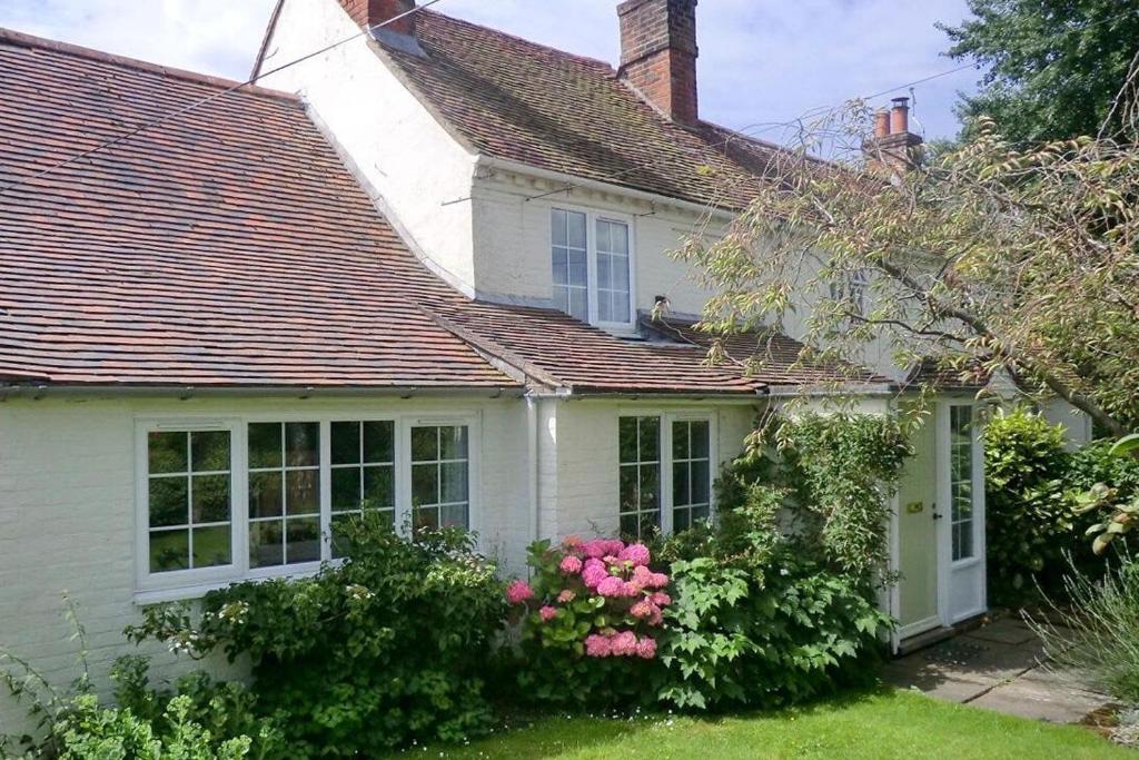 a white house with pink flowers in the yard at Pretty Cottage Near City & Sea in Fishbourne