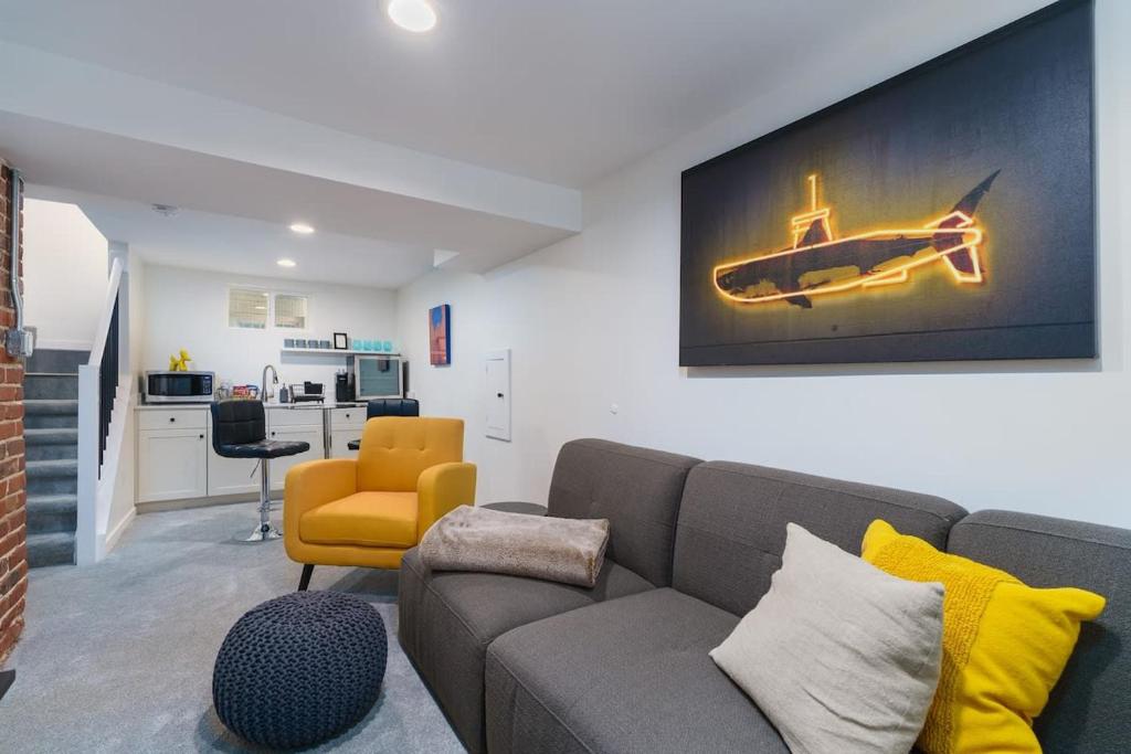 a living room with a couch and a yellow chair at Sleek & Stylish Apt Steps From Bluebird Theater in Denver
