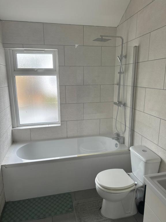 a bathroom with a white tub and a toilet and a window at City Dreams in Croydon