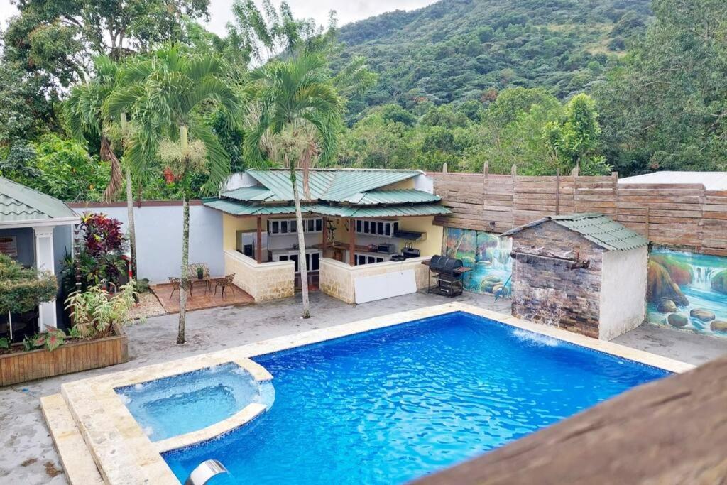 una imagen de una piscina frente a una casa en Villa con Hermosa Vista a las Montañas a Pasos del Río @drvacationsrental en Bonao