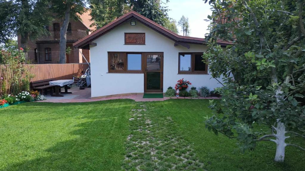 una pequeña casa blanca con un patio de césped en Domek z kominkiem, Ukta 63, Mazury,, en Ruciane-Nida