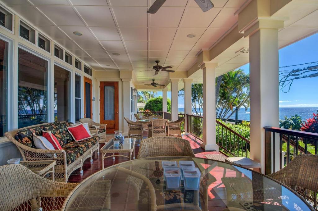 a porch with chairs and tables and a view of the ocean at Honu La'e in Koloa