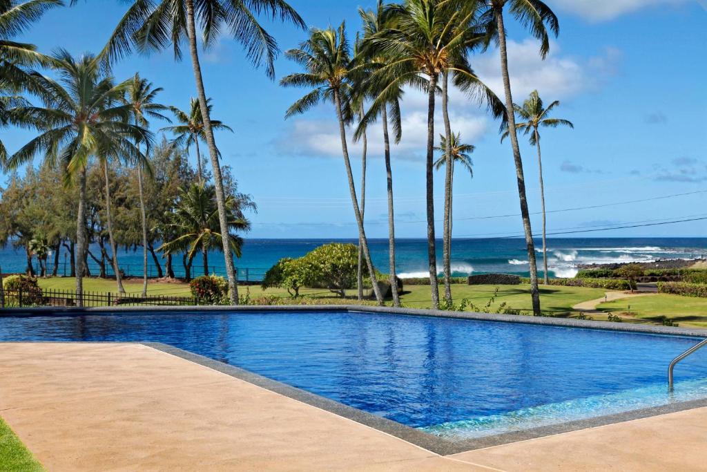 ein Swimmingpool mit Palmen und dem Meer in der Unterkunft Manualoha 101 in Kipu