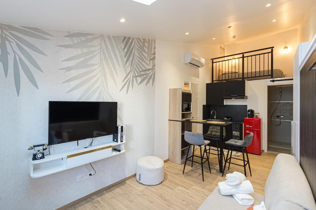 un salon avec une grande télévision à écran plat sur un mur dans l'établissement Charmant T1 Mezzanine Neuf Clim N•5 - Centre ville, à Montpellier