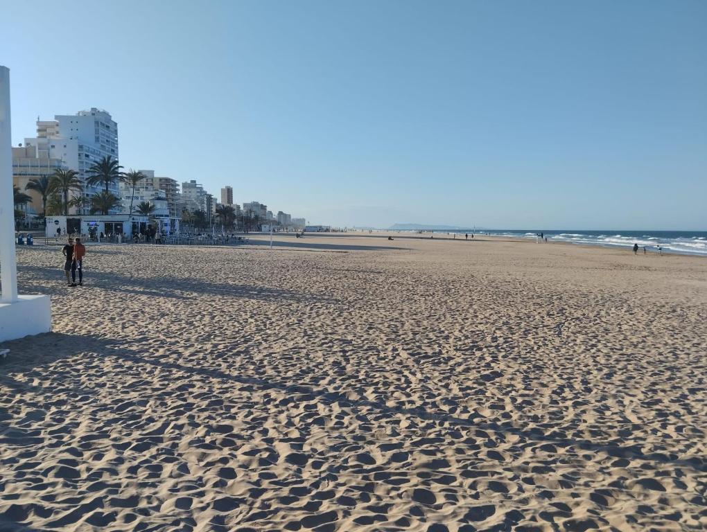 a beach with a person walking on the sand at Baleares III Apartamento a 100 metros de la arena in Los Mártires